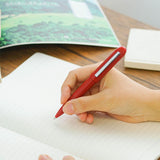 A red Bullet ballpoint pen held in hand.