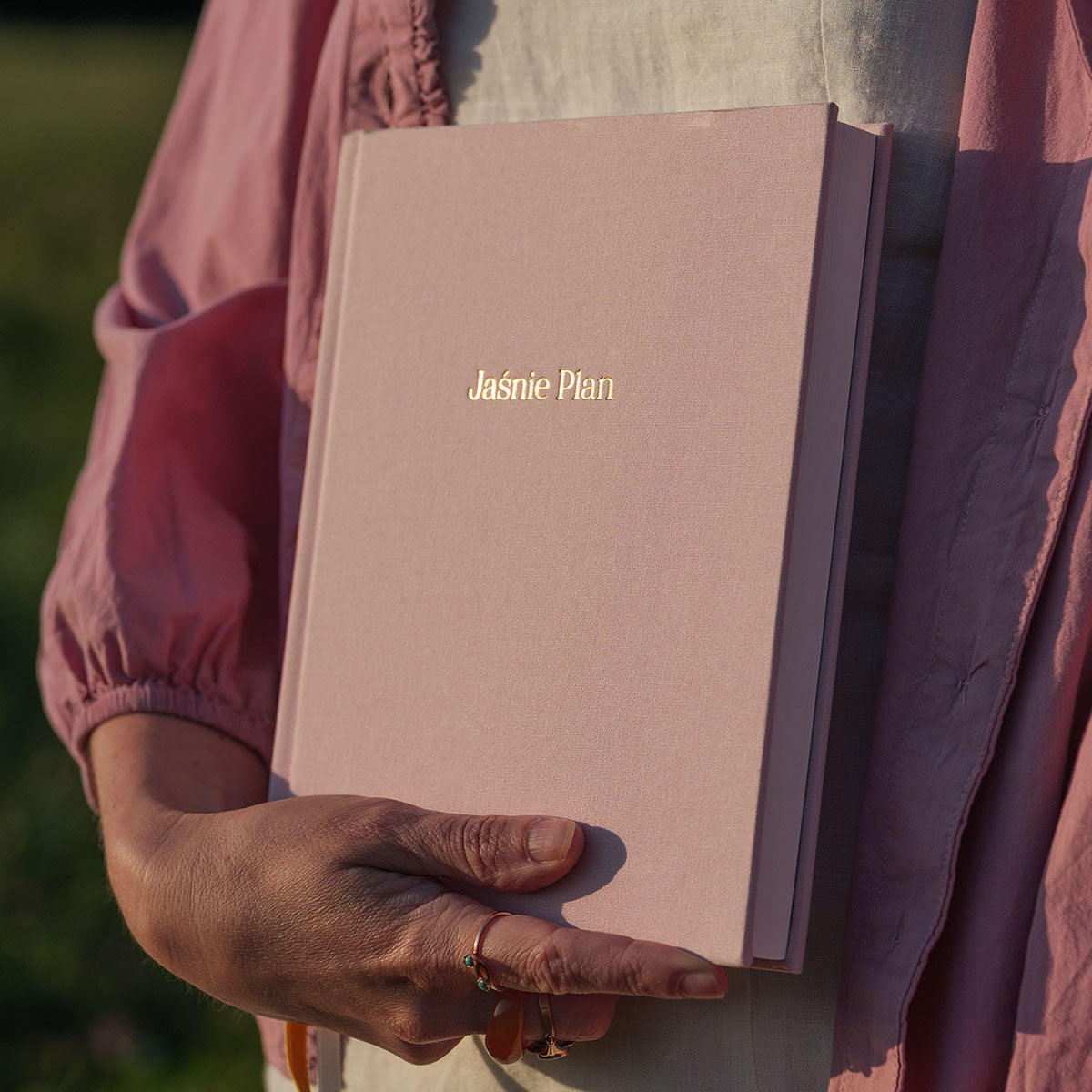 Planner Jaśnie Plan w kolorze baby pink trzymany w dłoni.