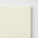 A cream-colored MD Product series notebook with green dot grid, open.