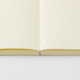 A cream-colored MD Product series notebook with green dots, opened flat.