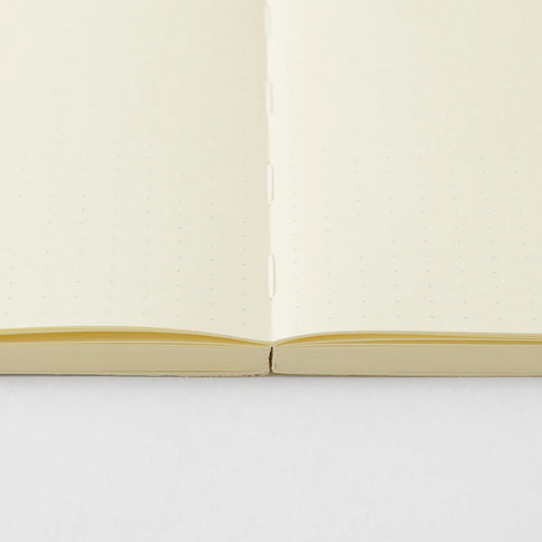 A cream-colored MD Product series notebook with green dots, opened flat.