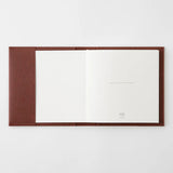 An open chocolate-colored paper cover in a square format with a notebook inside.