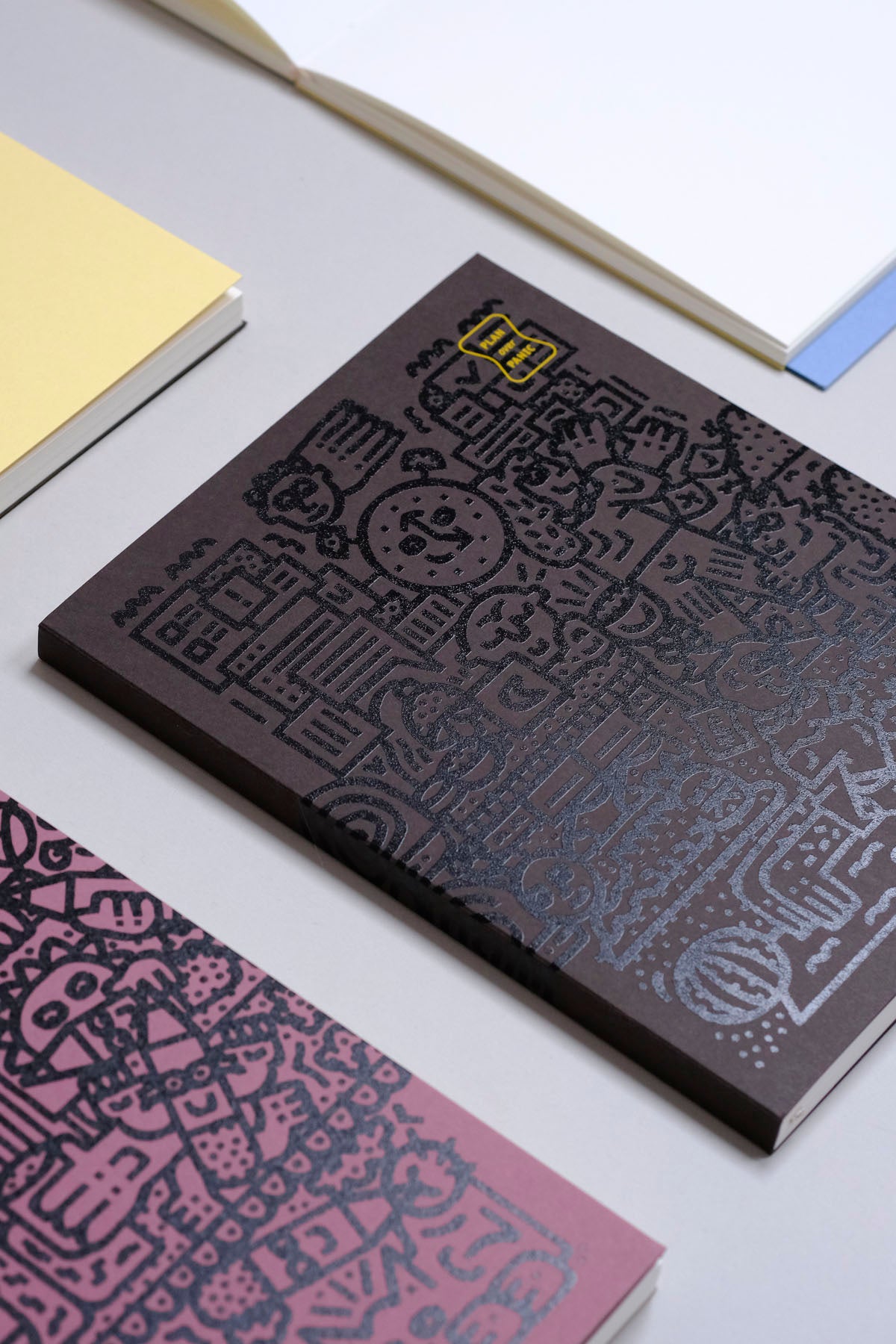 Brązowy planner z czarną grafiką od Tommy'ego Pieñczaka.