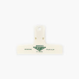 A cream plastic paper clip with a green logo featuring the Penco brand name.