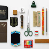 Steel scissors with green handles and the Penco brand name engraved on them, alongside other office supplies.