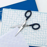 Open steel scissors with navy blue handles and the Penco brand name engraved on the blade.