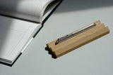 Caran d'Ache Ecridor Milanese Mesh fountain pen with an engraved silver-colored barrel on an oak stand.