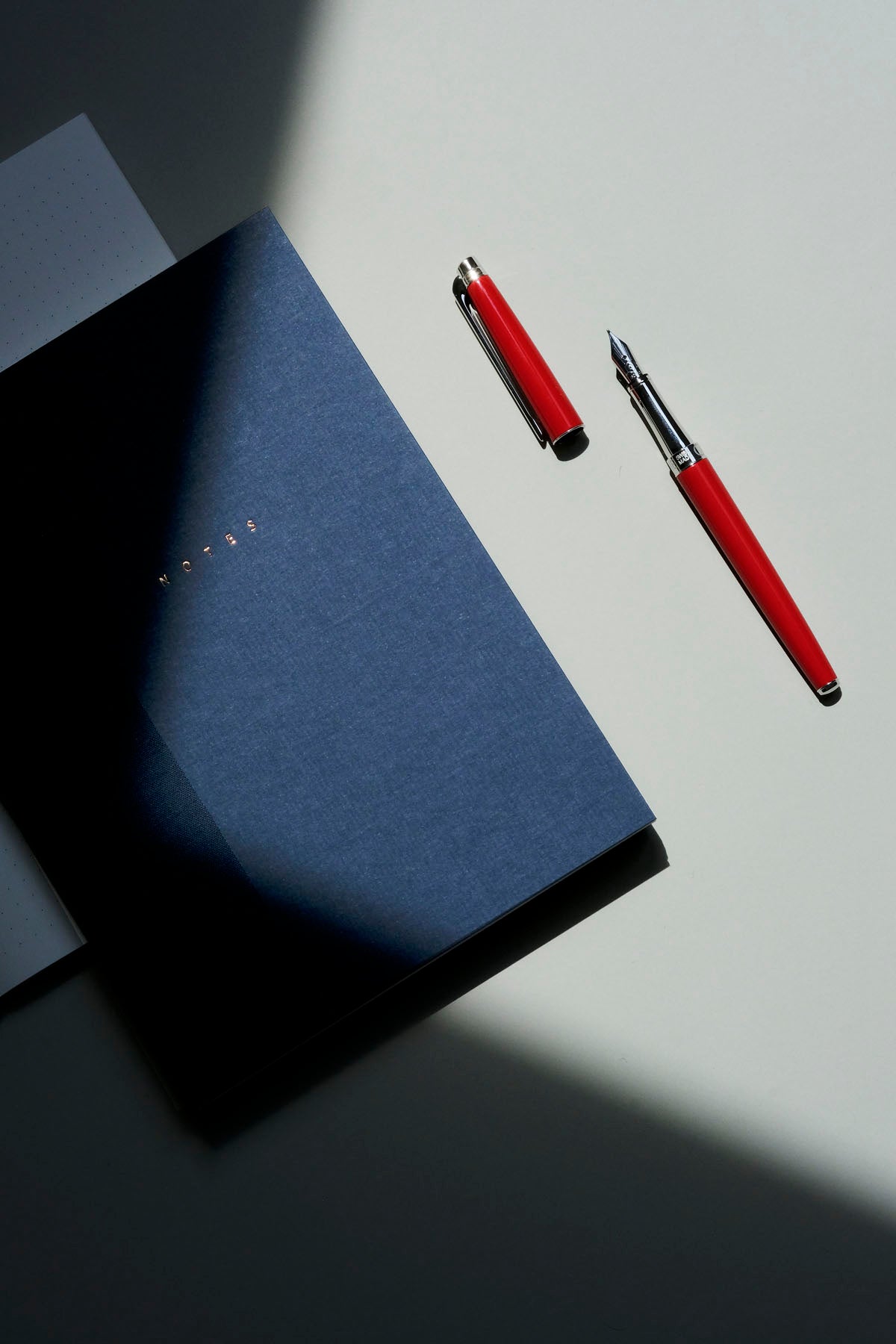 Notes Klasyk w kolorze granatowym a obok niego otwarte pióro Leman Slim Scarlet Red.