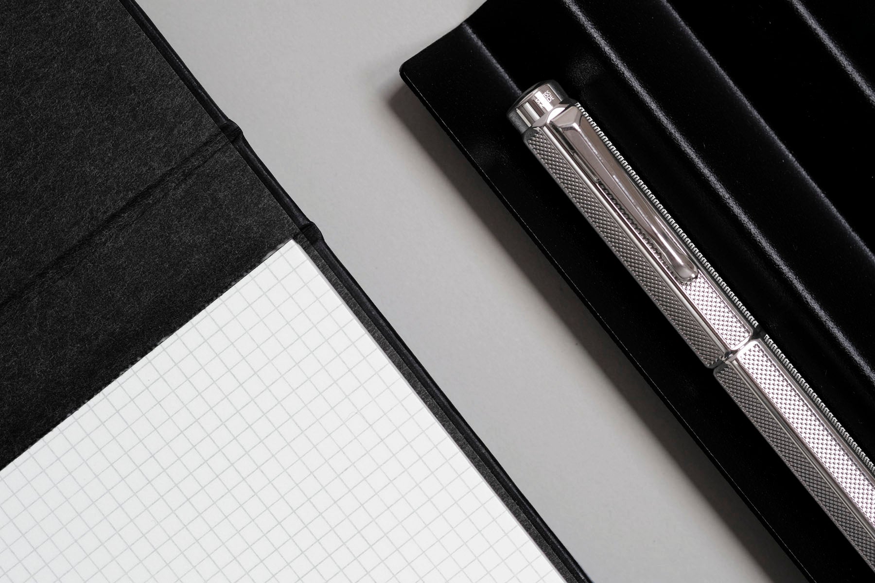 Work Pad z wyrywanymi kartkami w drobną kratkę oraz pióro wieczne w kolorze srebrnym.