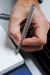 Caran d'Ache Ecridor Milanese Mesh fountain pen with an engraved barrel held in hand.