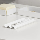 A white steel NAKA pen holder with a white pen placed on it.