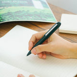 A green Bullet ballpoint pen held in hand.