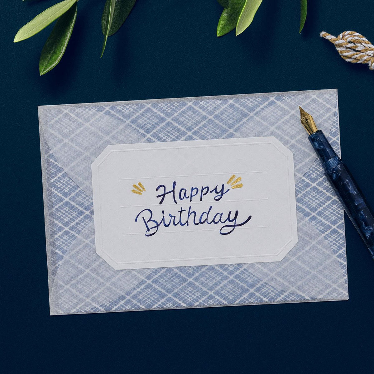 Półprzeźroczysta koperta zaklejona naklejką z napisem "Happy Birthday".