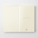 A cream-colored MD Product series notebook with green dots, opened flat.