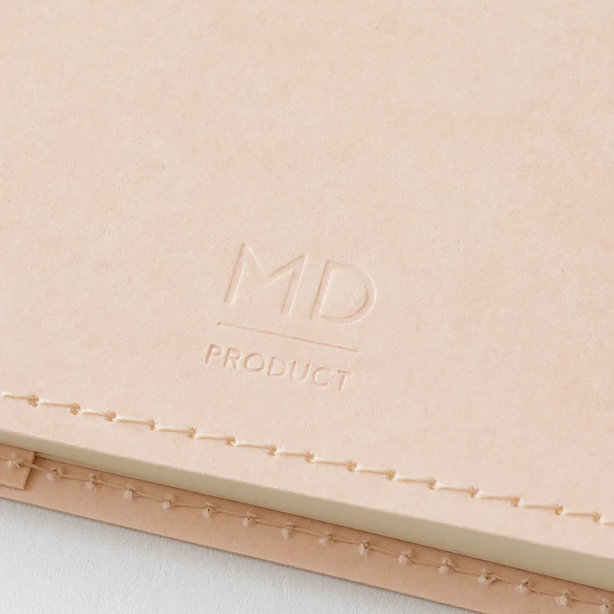 Tył papierowej okładki z tłoczonym logo Midori MD Product w kolorze cielistym.