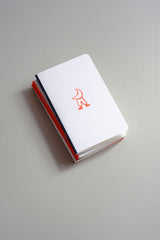 A small light grey notebook with an orange illustration.