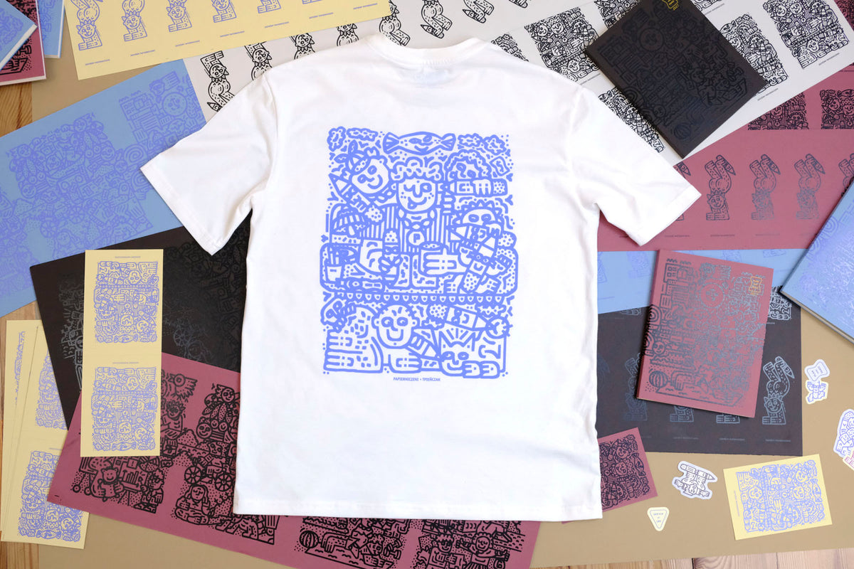 Tył T-shirtu z autorską grafiką TPieñczak na tle okładek notatników.