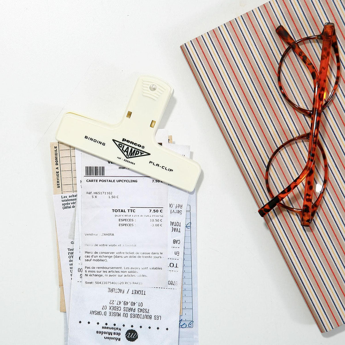 Plastikowy klips do papieru w kolorze kremowym spinający paragony.
